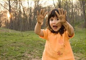 Young girl shows off muddy hands